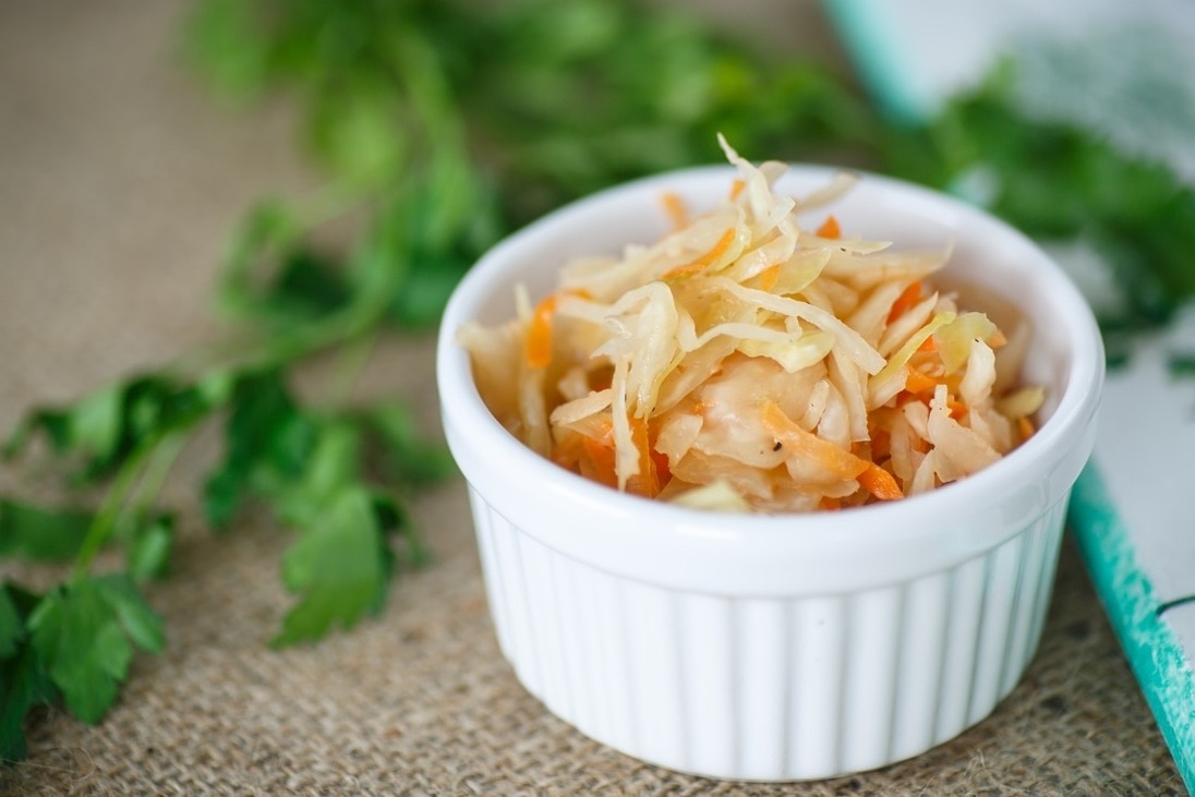 A ramekin of sauerkraut with fermented carrots drizzled with olive oil and a dash of pepper.